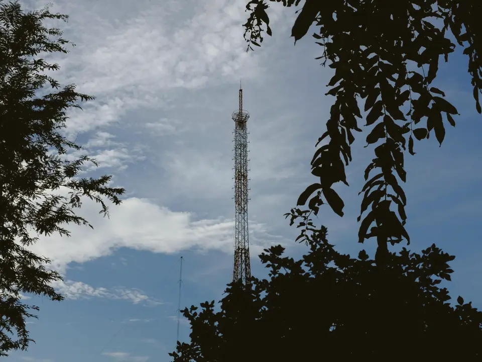 Communications tower against a blue sky, framed by trees